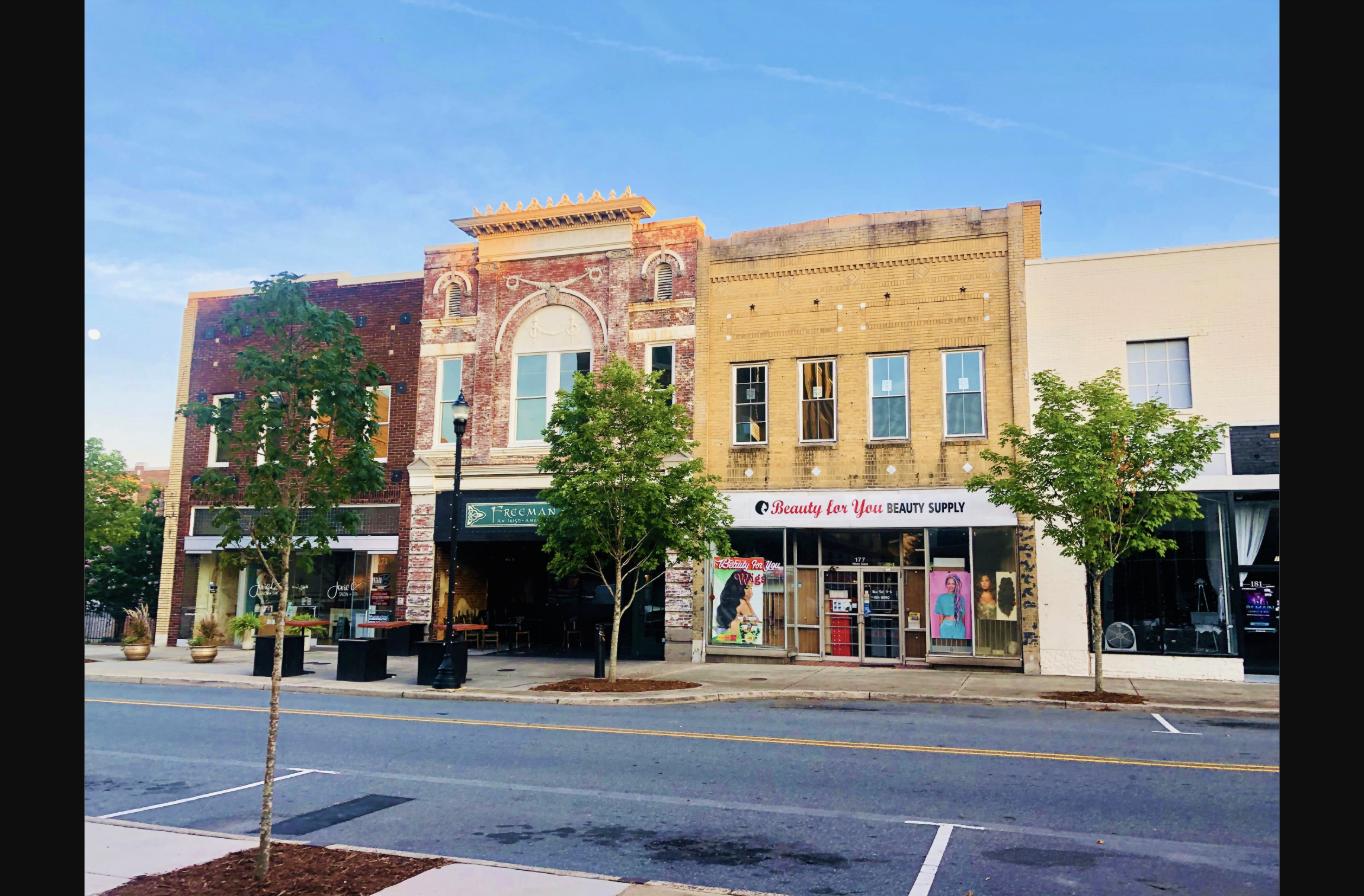 Gastonia, NC. Historic brick storefronts line a downtown street in Gastonia, North Carolina, with young trees planted along the sidewalk.