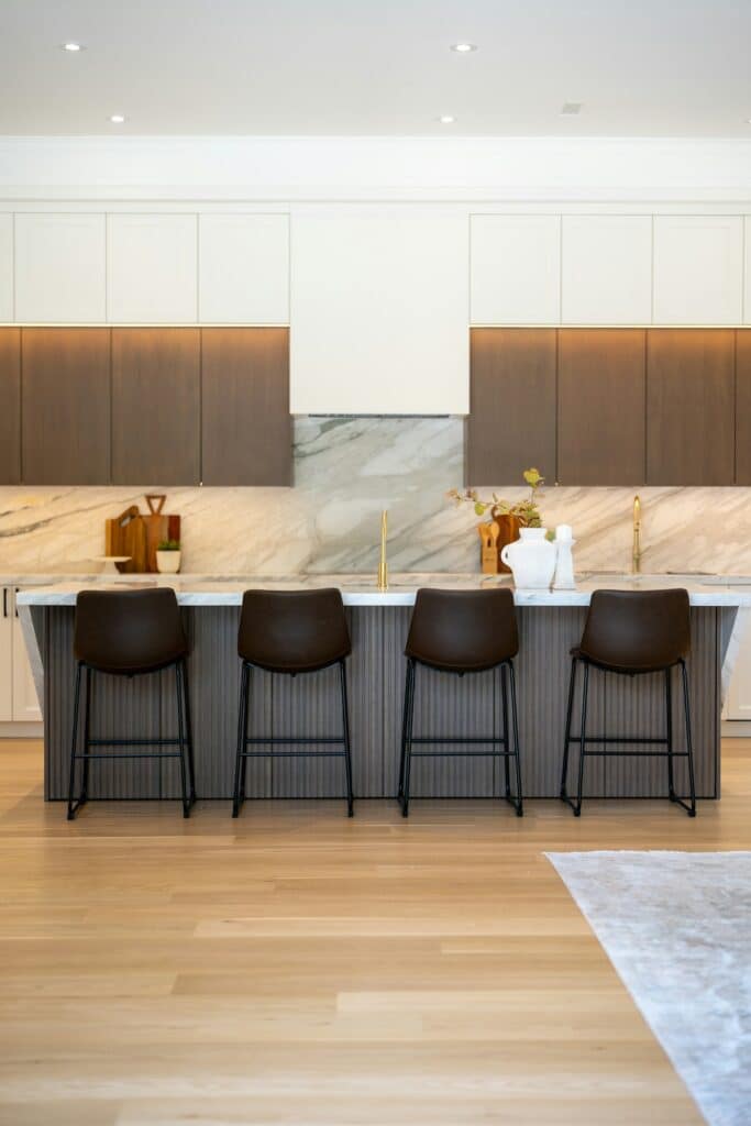 Kitchen with a veined stone backsplash and an island with four stools