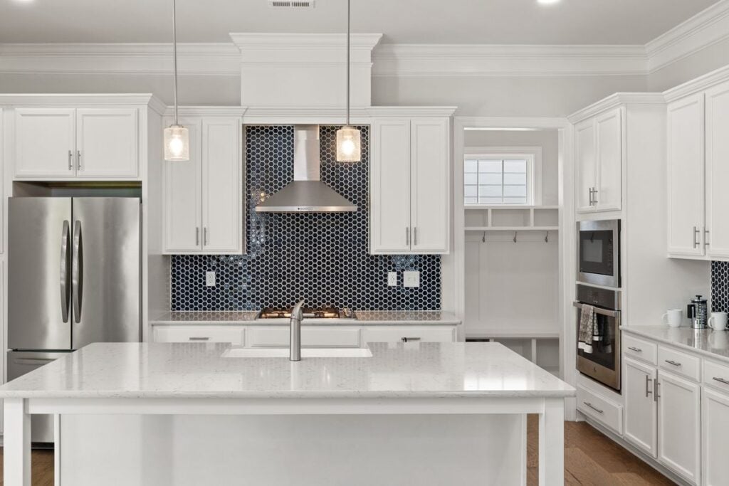 White kitchen with a navy hexagon tile backsplash behind the range