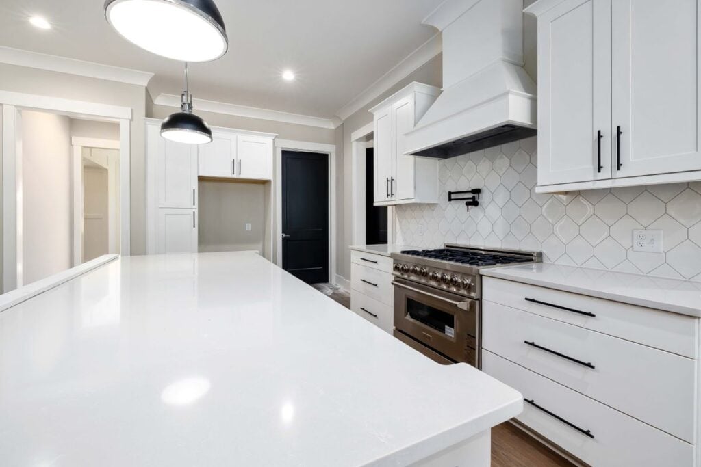 Kitchen countertops in Charlotte, NC: white kitchen with stone countertops along the main run and a patterned tile backsplash