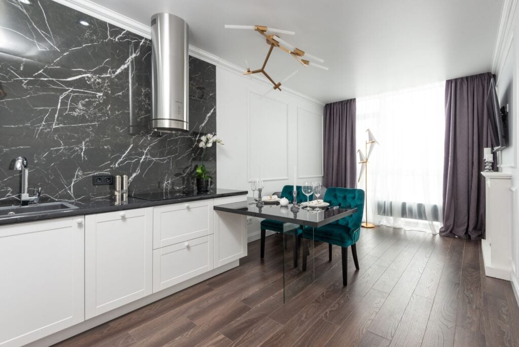 Example of a kitchen with a black marble backsplash and white cabinets