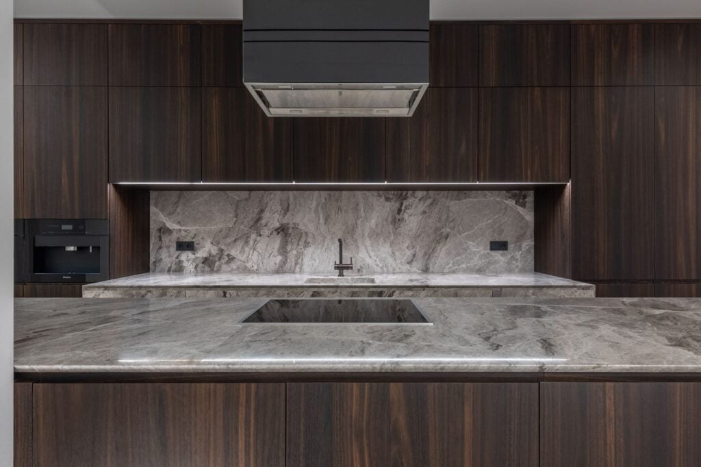 Kitchen with a quartzite slab backsplash and dark wood cabinets