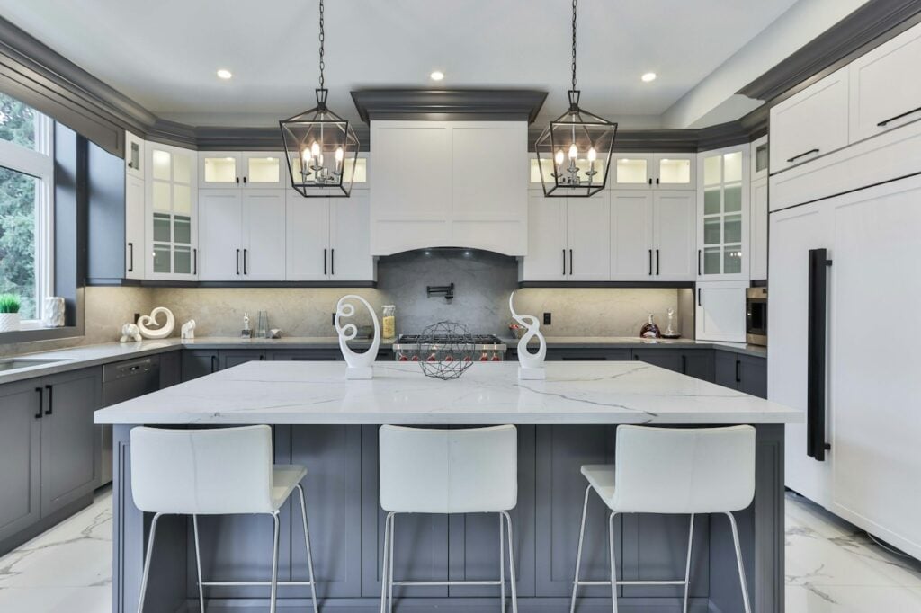 White and gray kitchen with a large island and lantern pendants